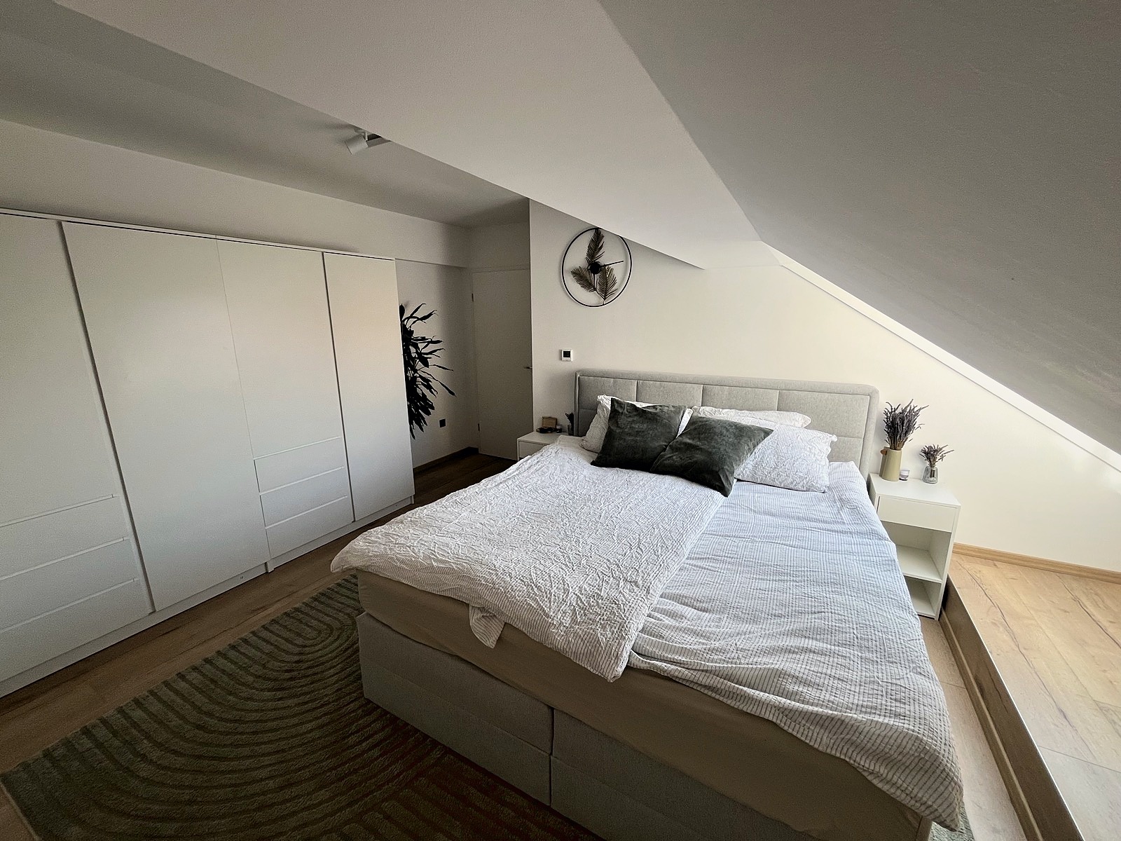 Master bedroom with king bed, sloped attic ceiling, and white wardrobe