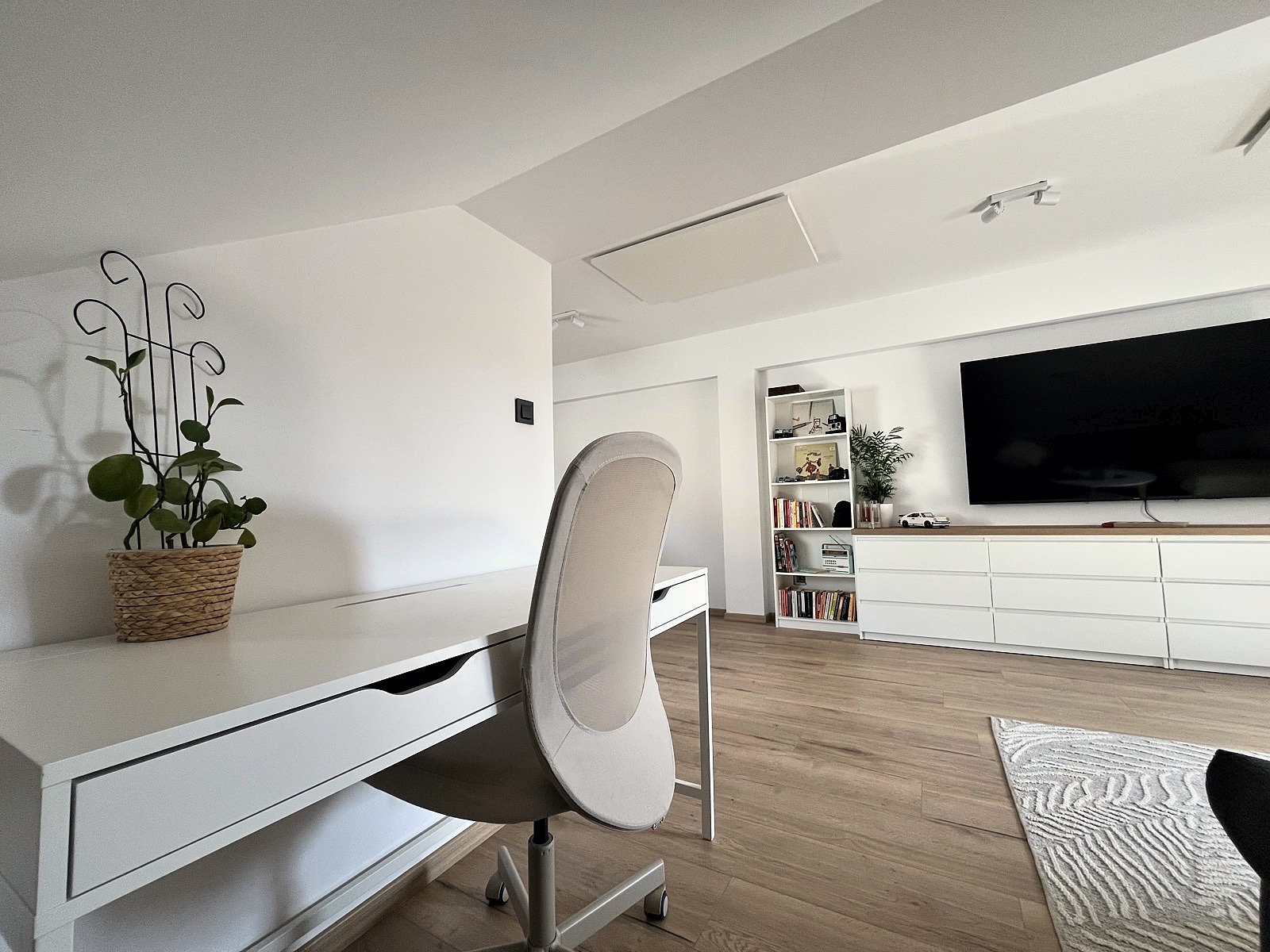 A white desk and ergonomic chair set up as a dedicated workspace